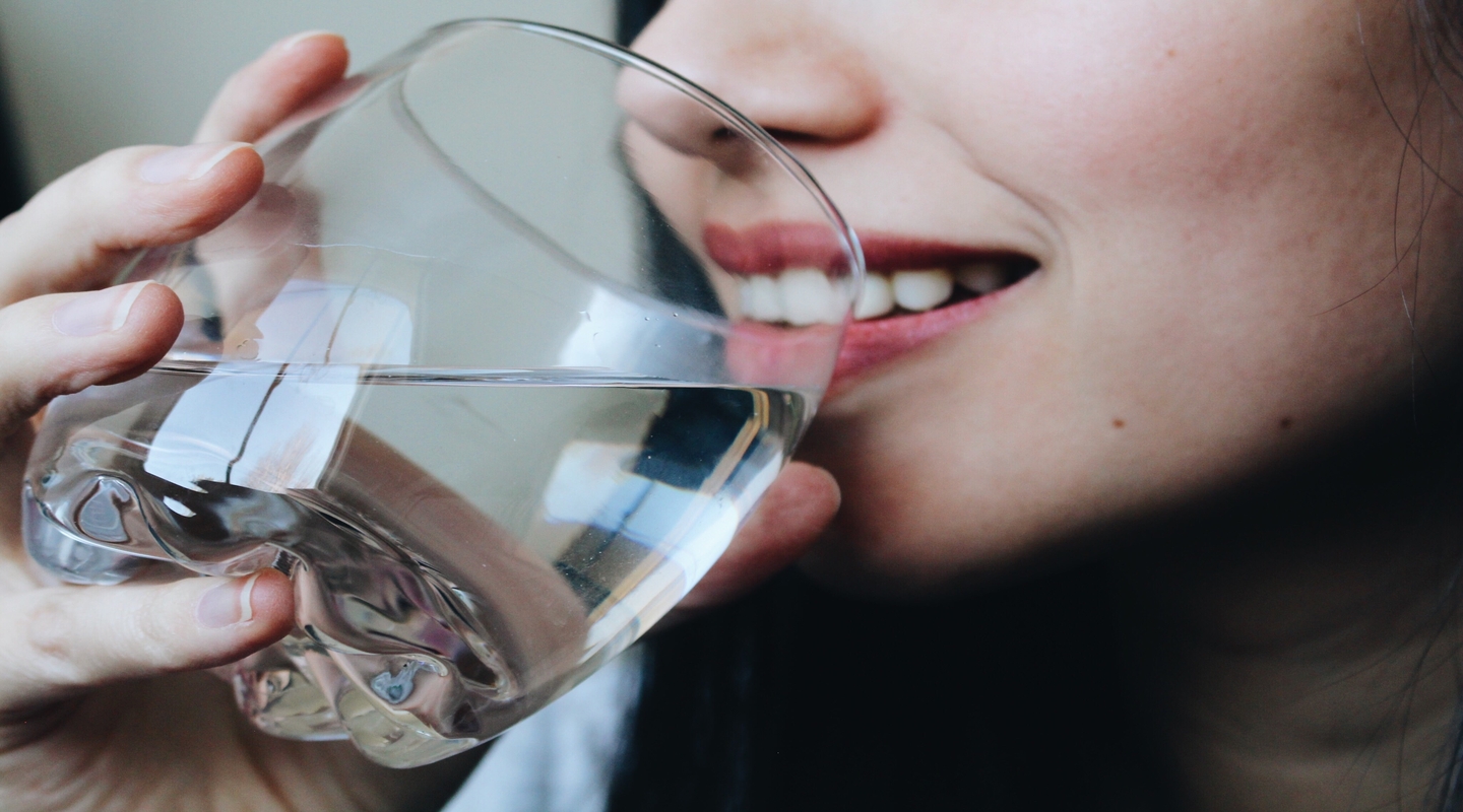 Žena pije vodu iz čaše